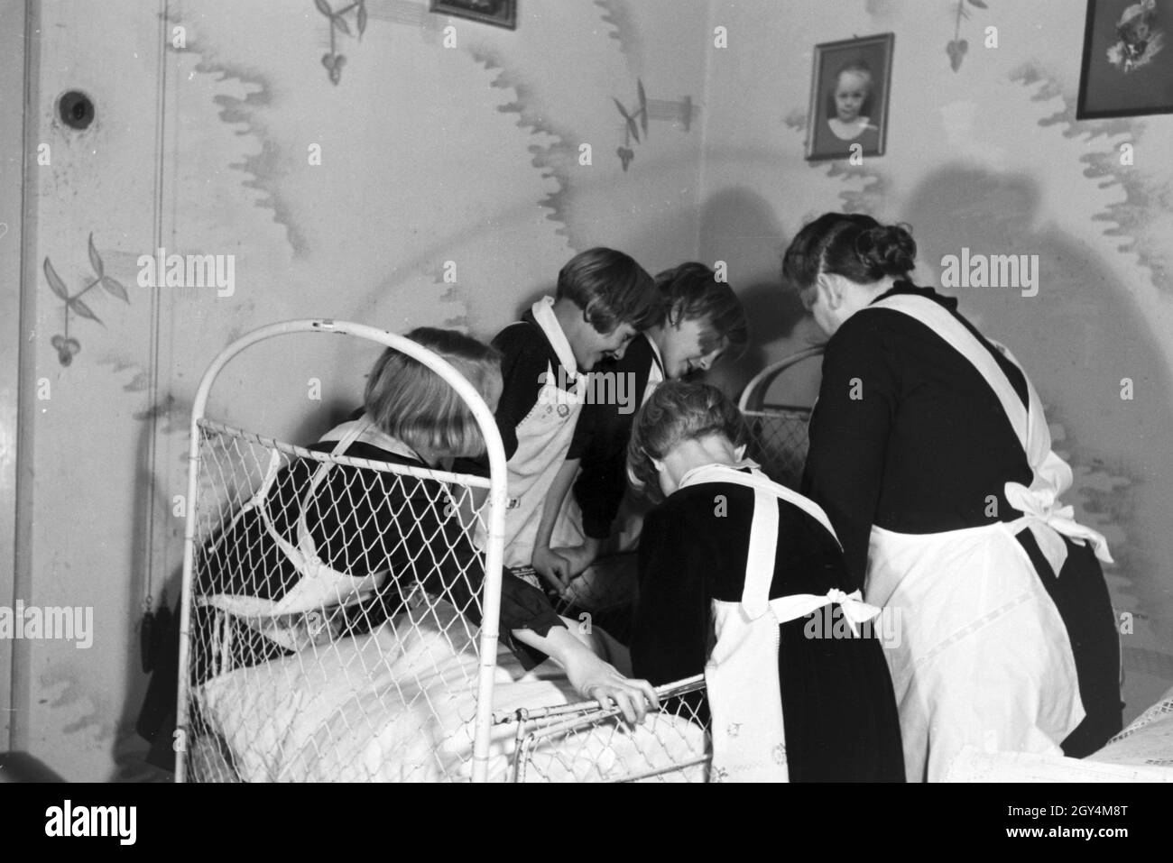 Die Vierlinge von Brücken stehen mit ihrer Mutter am Kinderbett ihres  jüngsten Geschwisterkindes, Deutsches Reich 1930er Jahre. The quadruplets  of Brücken standing with their mother at the crib of their youngest sibling,