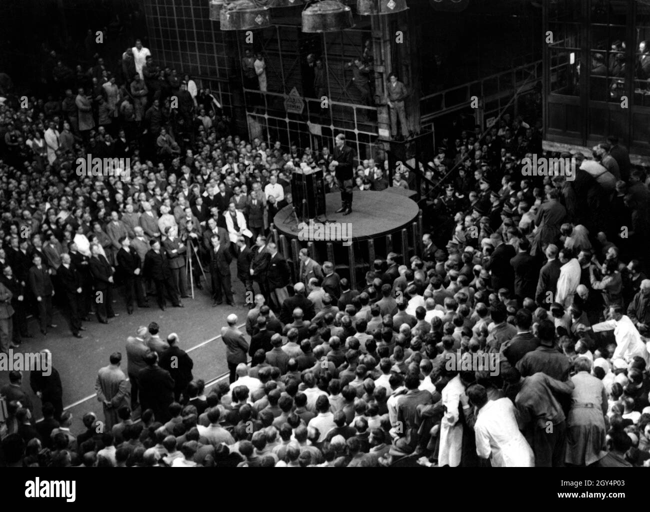 Adolf Hitler gives a speech in a machine hall at the Siemens-Schuckertwerke dynamo plant that was broadcast throughout Germany during the lunch break. Siemens dynamo plant in Nonnenallee two days before the Reichtstag election in 1933. [automated translation] Stock Photo