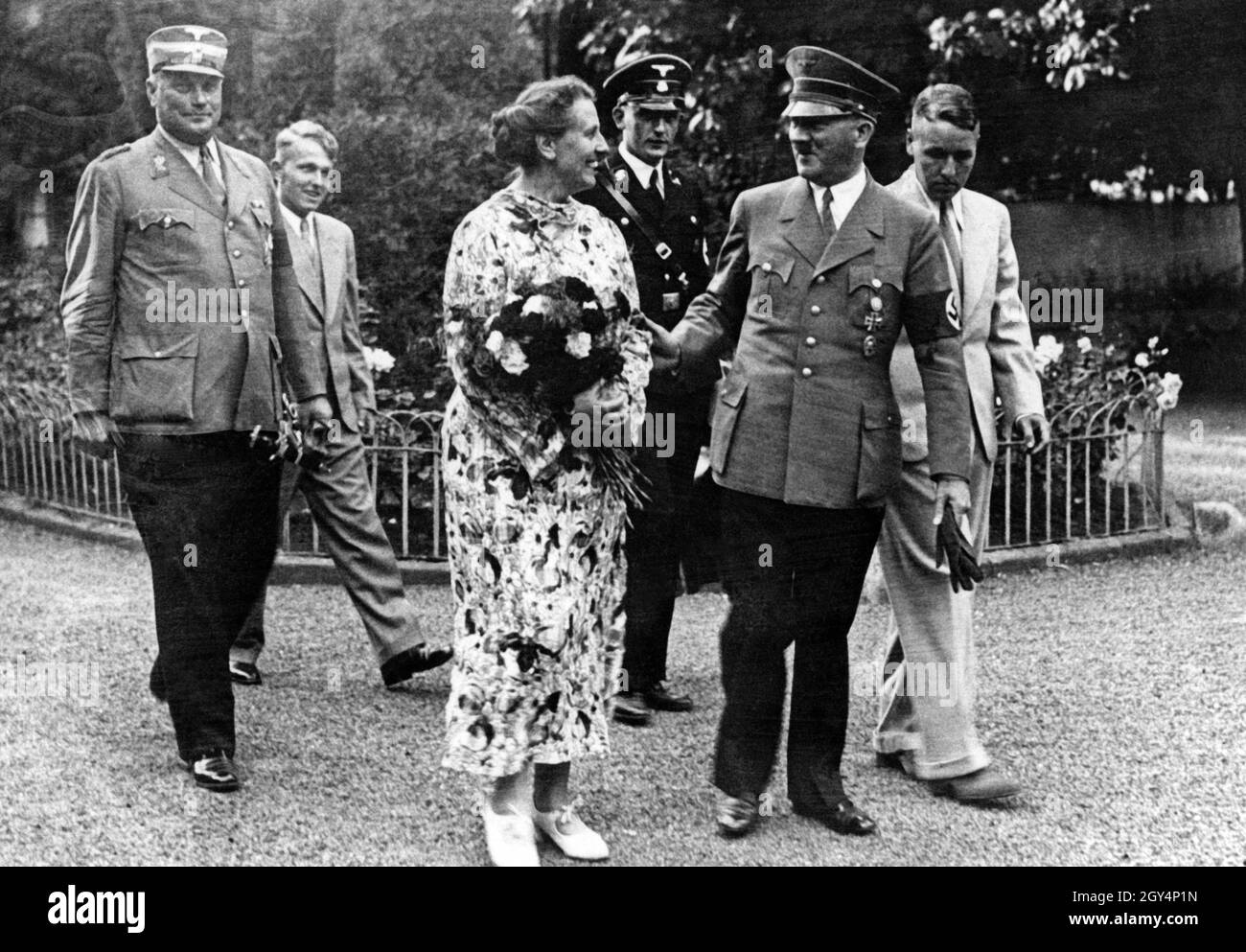 On the left are Wilhelm Brückner, Hitler's chief adjutant until that year, Winifred Wagner's son Wolfgang, the festival director Winifred Wagner, Richard Wagner's daughter-in-law, an SS man from Hitler's bodyguard (Führerbegleitkommando), Adolf Hitler and Richard Wagner's eldest son and grandson Wieland. Wolfgang later withdrew his mother's right to attend the festival when he was the director himself, after she repeatedly showed herself to be an old Nazi. Even without a year, this picture would easily date to 1940, as Hitler wore tails at the festival until that year. With the start of the Stock Photo