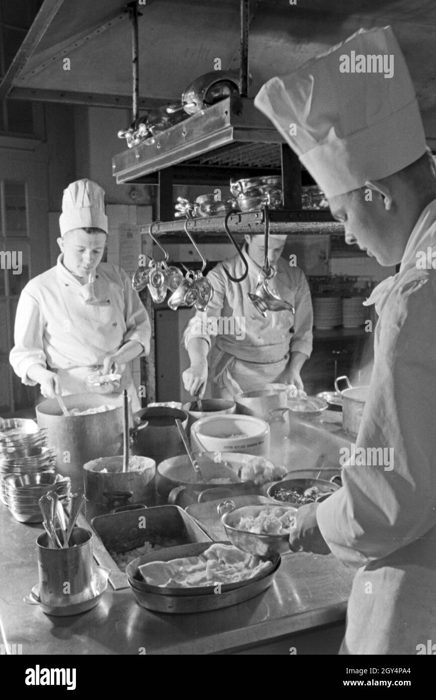 Köche bereiten eine Mahlzeit in der Küche einer Gaststätte, Deutschland 1930er Jahre.  Chefs preparing meals at the kitchen of a restaurant, Germany 1930s. Stock Photo