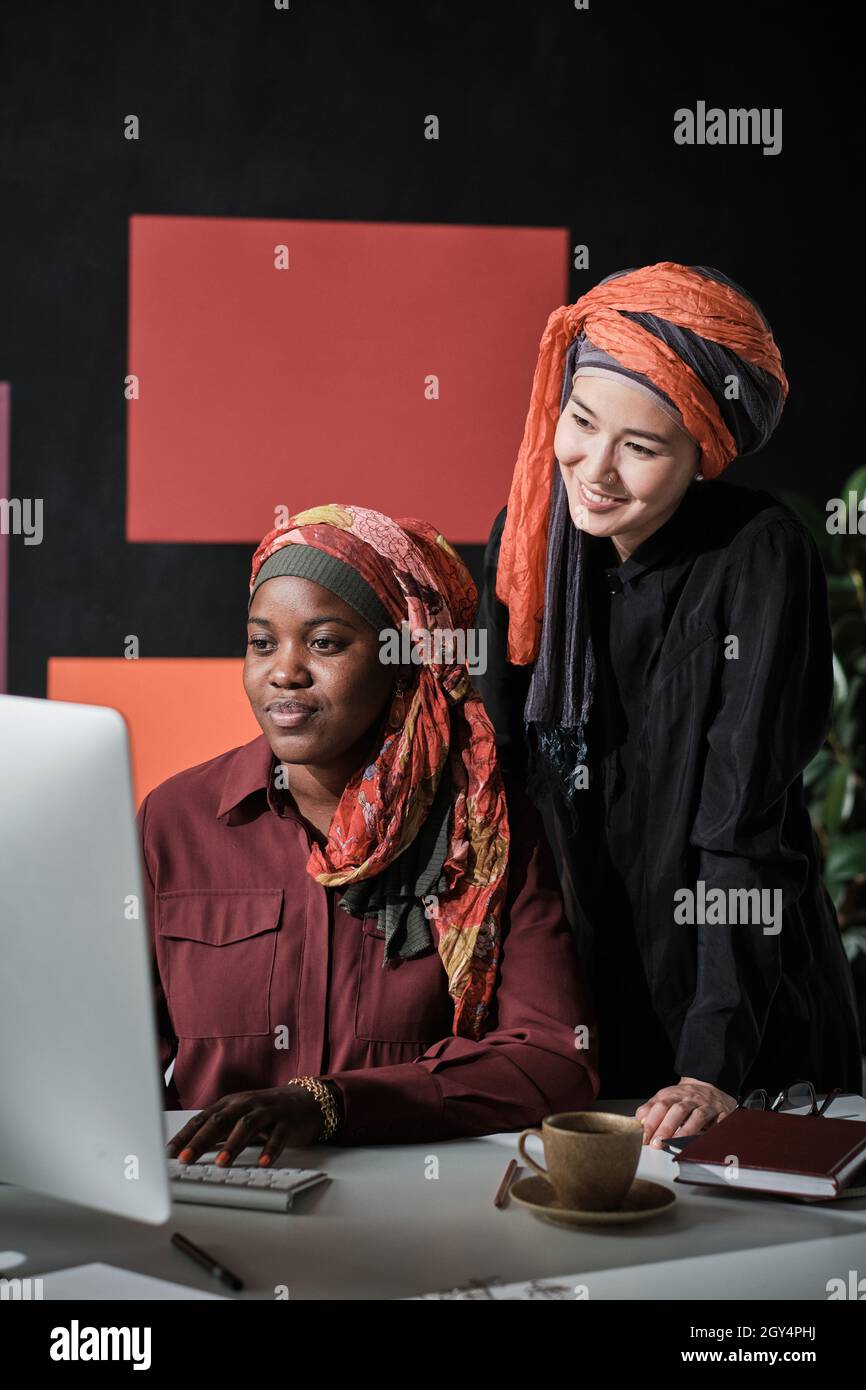 Two business colleagues in muslim clothing using computer in their teamwork at the table at office Stock Photo