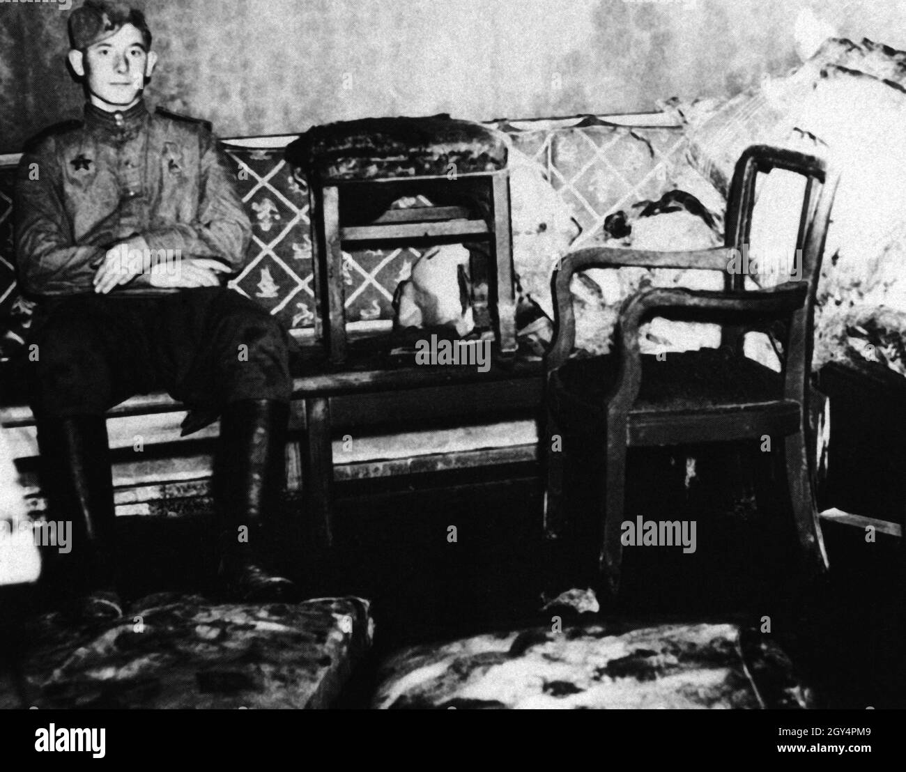 The picture, taken by an American soldier in early July, shows a Red Army soldier in the room in the Führerbunker, the study where Adolf Hitler and Eva Braun committed suicide. With his boots, the soldier stands on the upholstered parts of the sofa on which Adolf and Eva Hitler killed themselves. [automated translation] Stock Photo