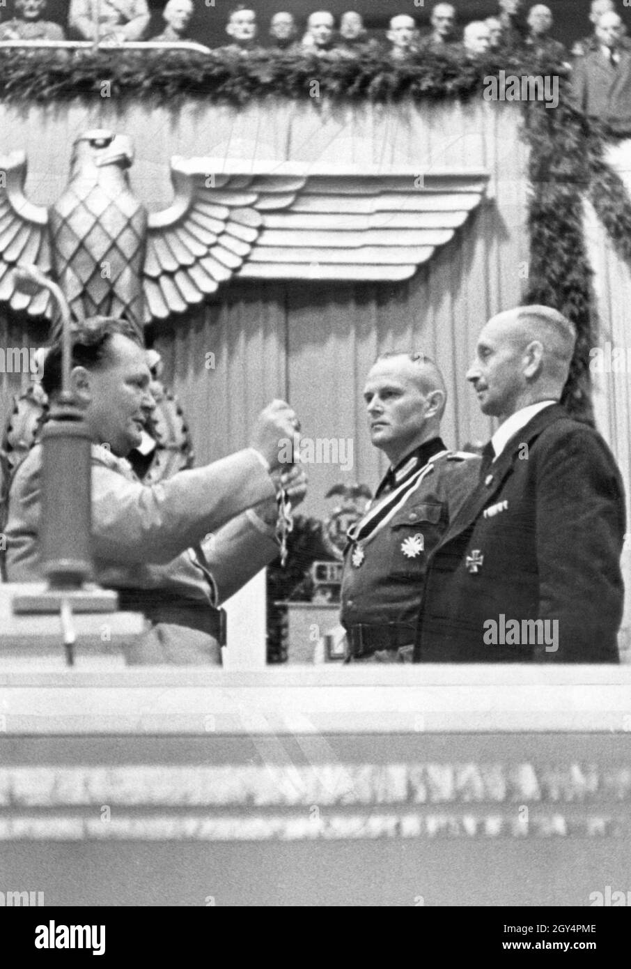 'On October 4, 1942, Thanksgiving Day, Reichsmarschall Hermann Göring (left) gave a ''Thanksgiving speech'' at the Sportpalast in Berlin-Schöneberg. In the speech he assured to secure food for the ''German people'' in the approaching winter. In the picture, Göring awards the Knight's Cross of the Order of Merit of the War to the farmer leader Ernst Ritter (black suit) and farmer leader Fritz Leffler (next to him on the left). [automated translation]' Stock Photo
