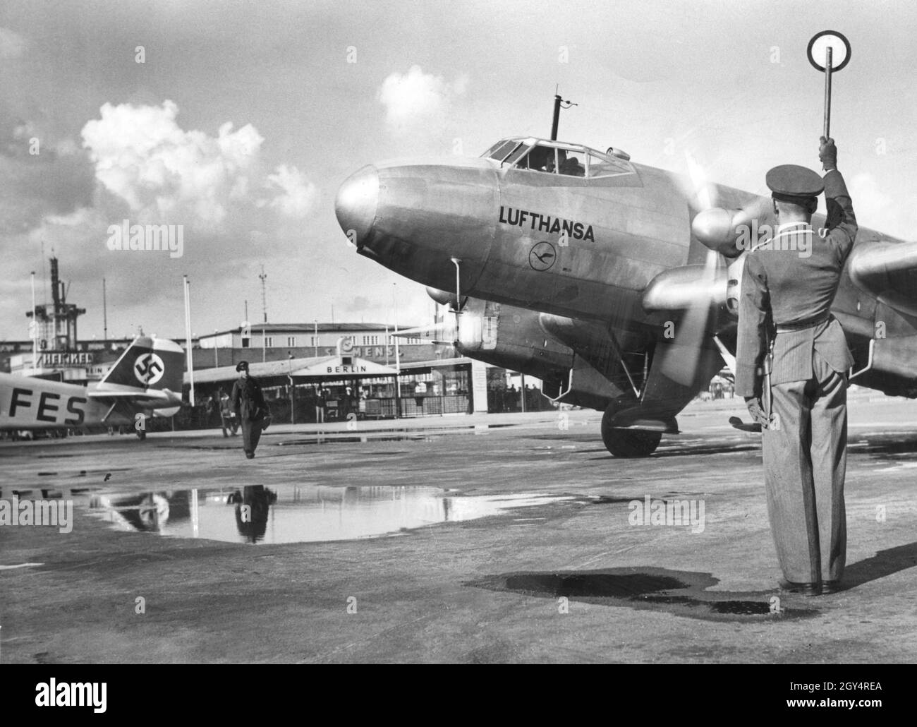 A ground controller gives a signal to the pilot of a Lufthansa Junkers Ju 86. The photograph was taken in 1937 at Berlin-Tempelhof Airport. [automated translation] Stock Photo