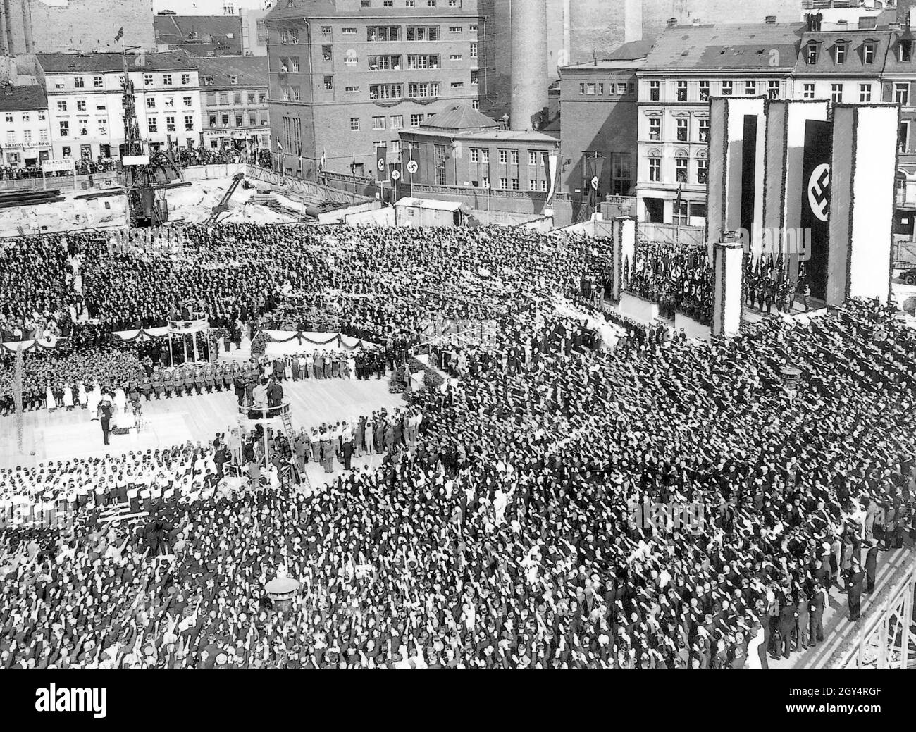 'On May 5, 1934, the cornerstone was laid for the house on Werderscher Markt, which served as an extension to the Reichsbank. A crowd of people saluting Hitler attends the event, including sections of Nazi organizations such as the Hitler Youth and the Bund Deutscher Mädel (left in the picture). The ''Deutschlandlied'' is being played. Two round, raised platforms have been erected especially for the picture and film press. Adolf Hitler and Hjalmar Schacht were present at the ceremony. [automated translation]' Stock Photo