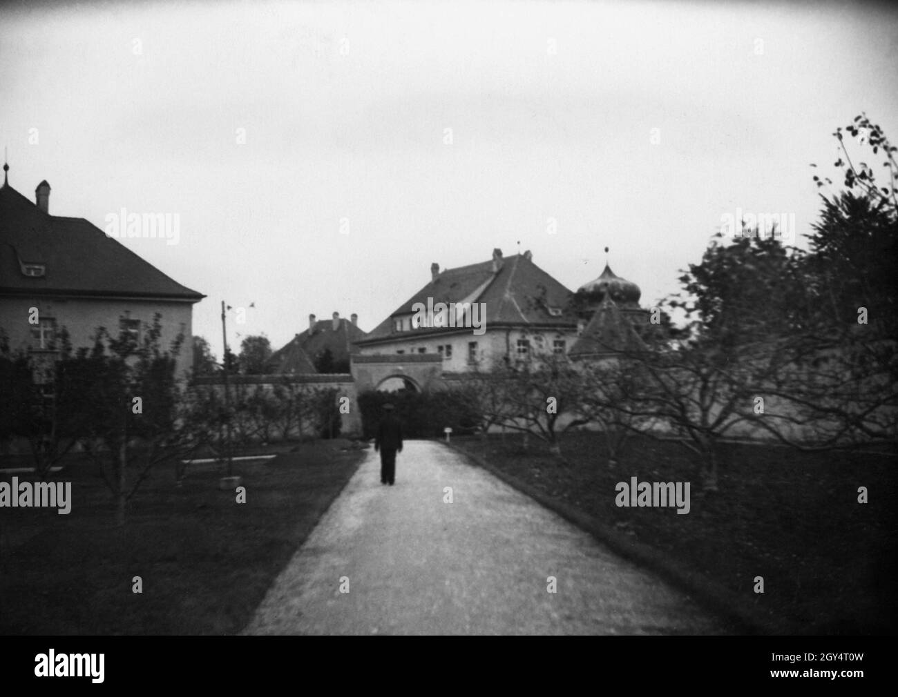 'A man walks in the fortress garden of the ''State Prison'' in Landsberg am Lech in 1933. The entrance building to the prison is in the background. In the garden, Adolf Hitler was allowed to receive friends and followers during his imprisonment in the fortress and to go for a walk. [automated translation]' Stock Photo