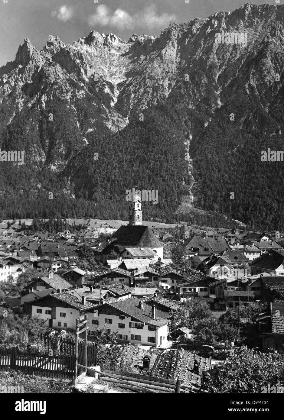 This photograph, taken in 1938, shows the climatic health resort of Mittenwald with the church of St. Peter and Paul in the center. The Northern Karwendel range rises up behind the town. [automated translation] Stock Photo