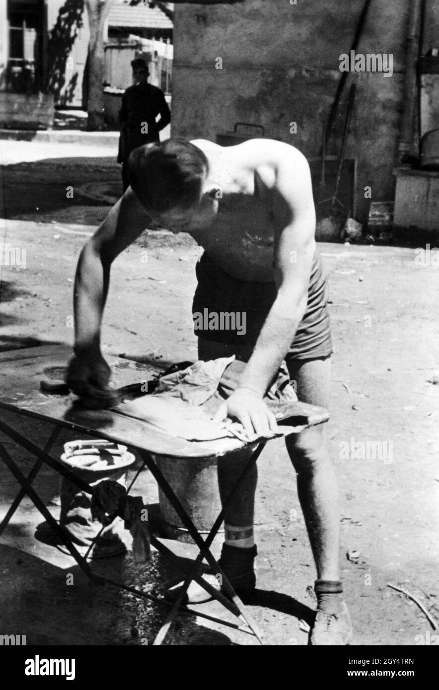 A soldier of the German Wehrmacht irons his laundry in his quarters in