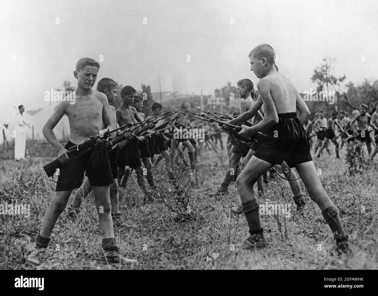 At a tent camp in the summer of 1934, boys belonging to the fascist youth organization Opera Nazionale Balilla practiced handling the bayonet in single combat. In the Balilla, the youths were drilled athletically and militarily for later entry into the army. The picture was taken in mid-August in Grottaferrata, southeast of Rome, the location of the holiday camp. [automated translation] Stock Photo