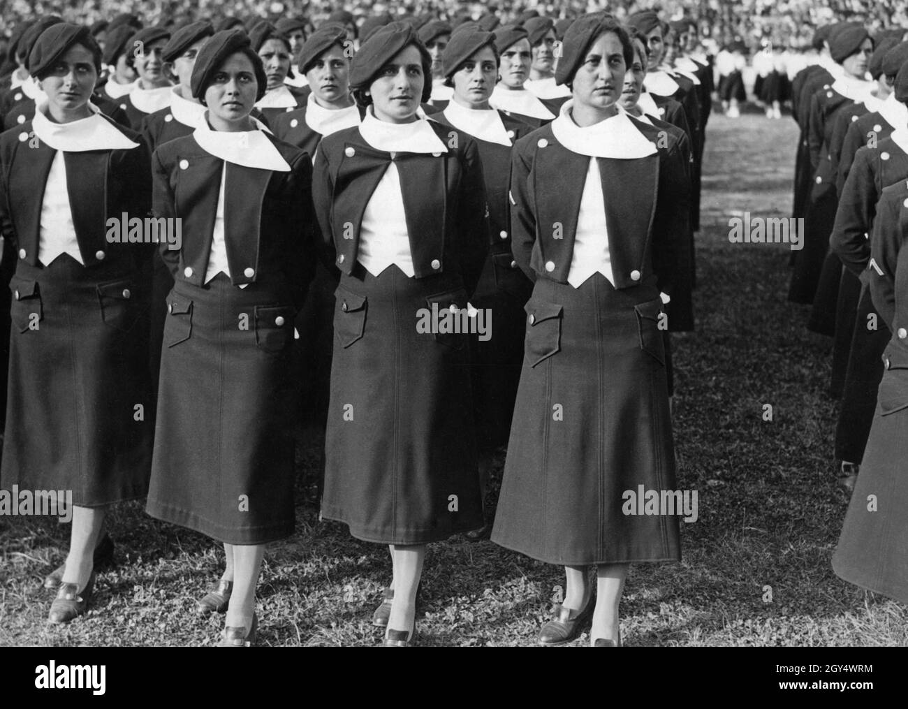 'Young women belonging to the ''Giovani Fasciste'' gathered for a roll call in an Italian stadium in 1937. The group leader stands in front on the right. The Giovani Fasciste included women aged 18 and over. [automated translation]' Stock Photo