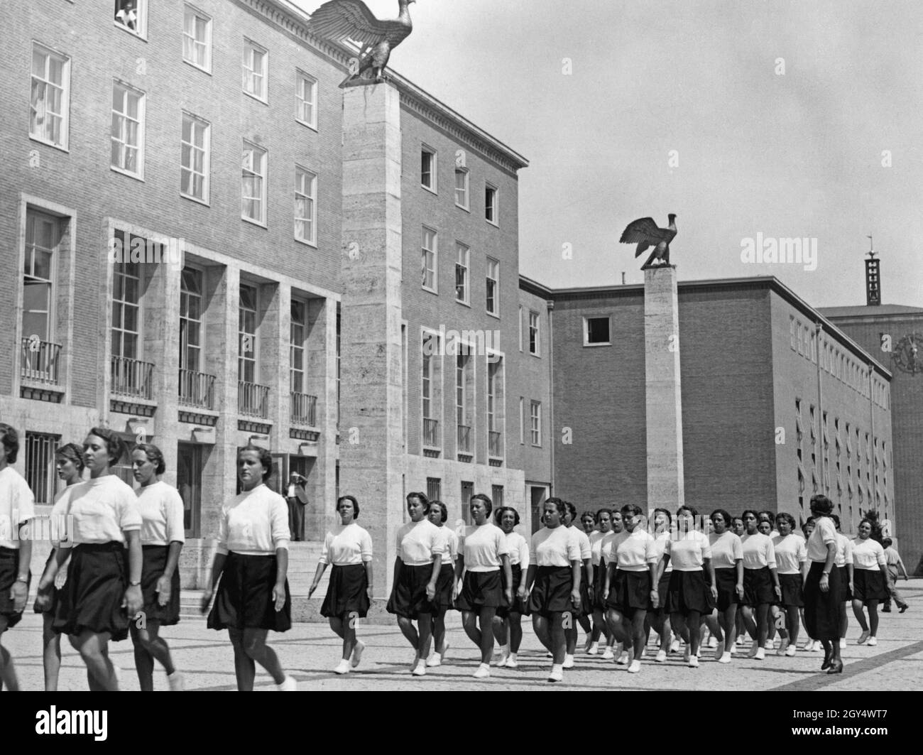 'On Sunday, June 13, 1937, 1200 members of the Opera Nazionale Balilla arrived at the Anhalter Bahnhof in Berlin. Among them was a detachment of girls from the ''Giovani Italiane'', who were accommodated on the Reichssportfeld. The picture shows the Italian girls on their way across the Adlerplatz to the early morning sports on the Olympic grounds. The German Sports Forum is in the background. [automated translation]' Stock Photo