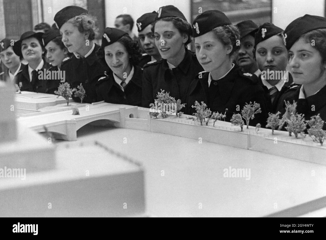 The picture shows a group of young women from Italy who belong to the fascist Opera Nazionale Dopolavoro (OND). They are in the anteroom of the Haus der Deutschen Kunst (now Haus der Kunst) in Munich, where they are looking at architectural models showing the German Nazis' plans for more monumental buildings. The Italian women were able to vacation in Munich through the OND. The OND was the Italian Fascists' leisure and recreation organization and the mass Fascist organization with the largest membership. Undated photograph, probably taken in the late 1930s. [automated translation] Stock Photo