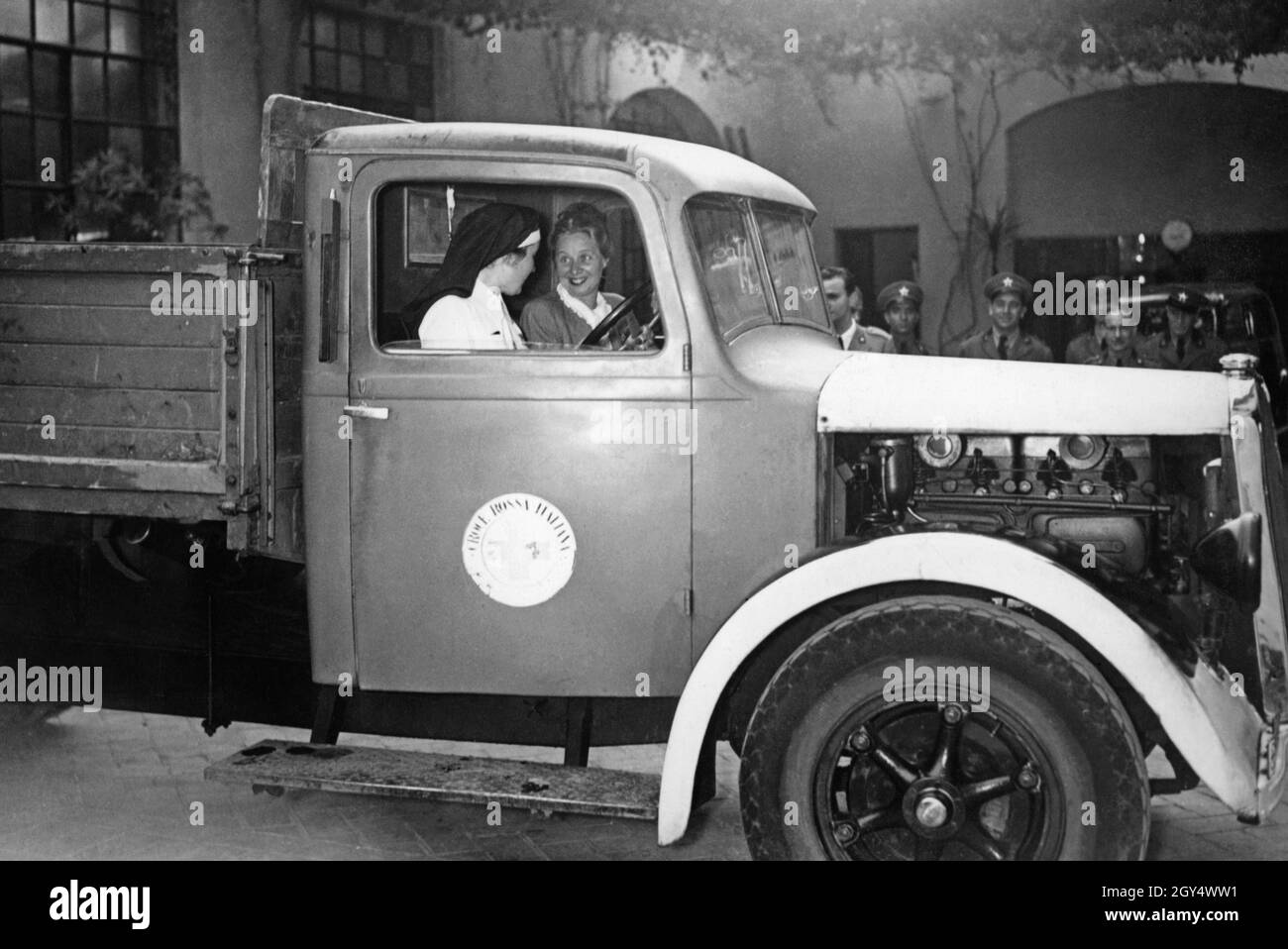 These two women are driving an ambulance of the Italian Red Cross. In the background some men are standing and watching them. The photograph was taken in 1940. [automated translation] Stock Photo