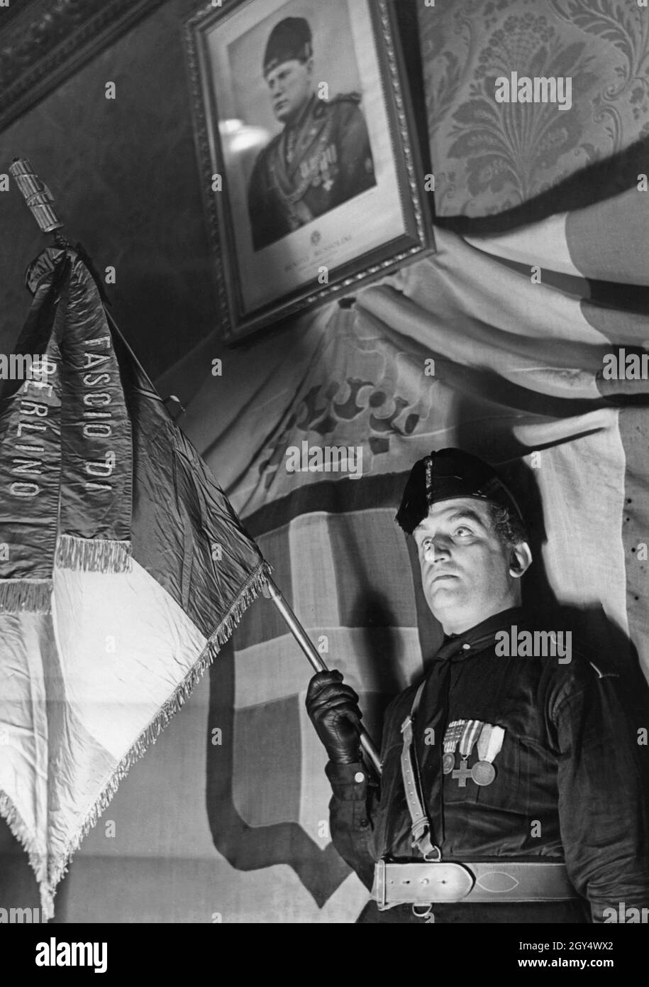 The Italian fascist group in Berlin (Fascio di Berlino) received a flag from Mussolini. The flag bearer is standing under a portrait of the dictator Benito Mussolini. The photograph was taken in 1933. [automated translation] Stock Photo