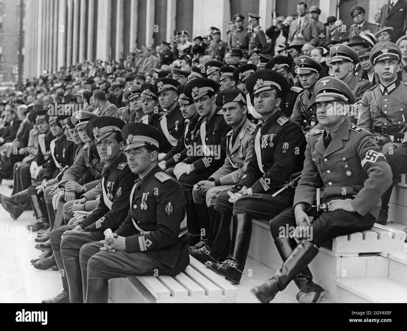 'On May 1, 1937, the big rally for the ''National Holiday of the German People'' took place in Berlin-Mitte. On a grandstand in the Lustgarten, Italian Balilla officers (black uniforms) from the entourage of youth leader Renato Ricci watched the parade alongside HJ officers. On the far right sits an area leader of the Hitler Youth. [automated translation]' Stock Photo