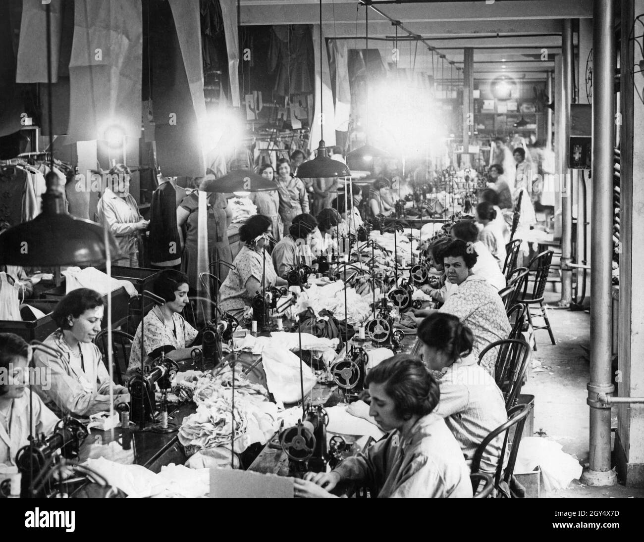 Workers sewing garments in a textile factory in the USA. [automated