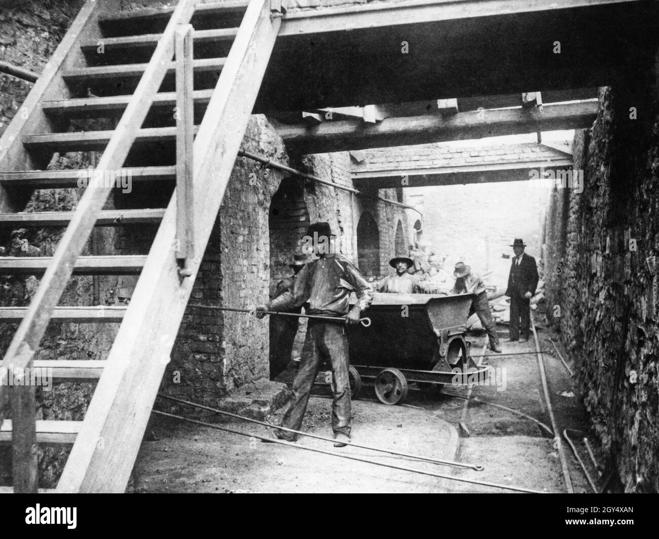 Workers in a zinc smelter in Upper Silesia scraping out the waste in