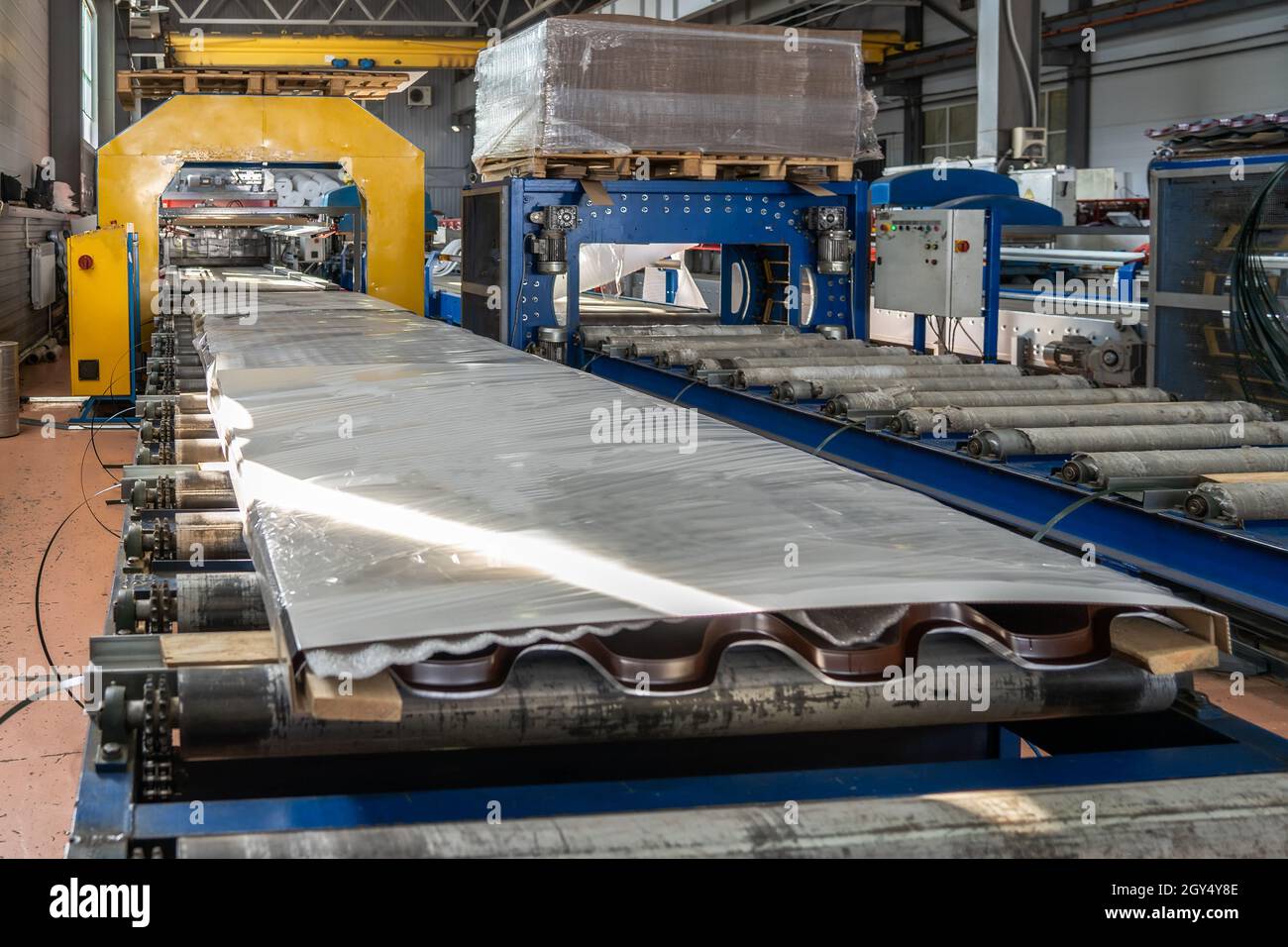 Conveyor with finished packaged products of metal tile sheets for roof