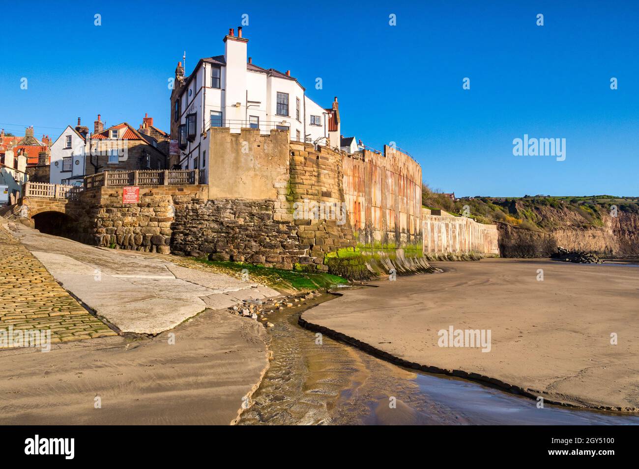 The sea wall and village of Robin Hood's Bay, North Yorkshire, from the foreshore on a spring morning. Stock Photo