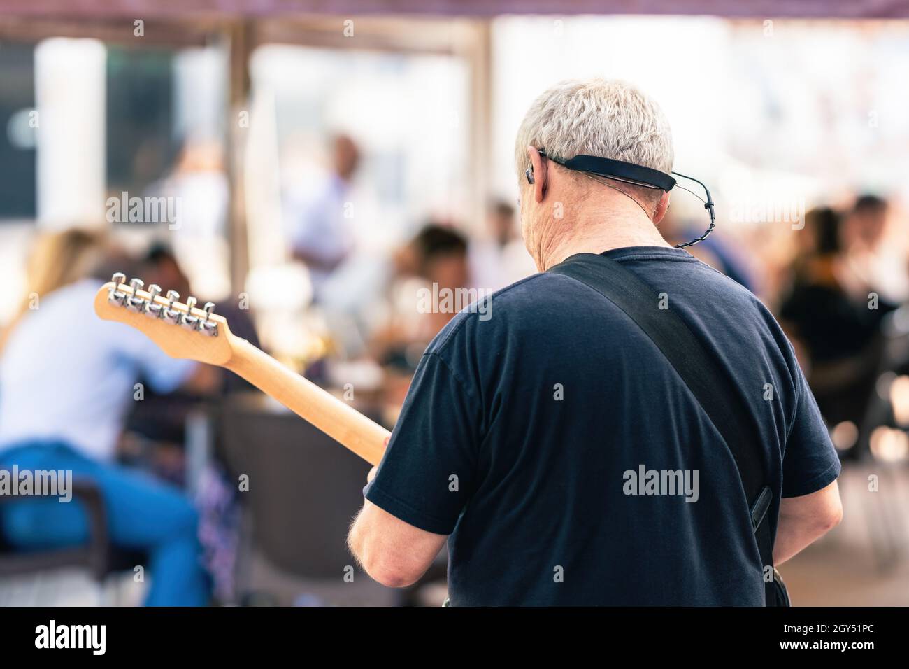 Back of an elder man playing the electric guitar on a live concert in the terrace Stock Photo