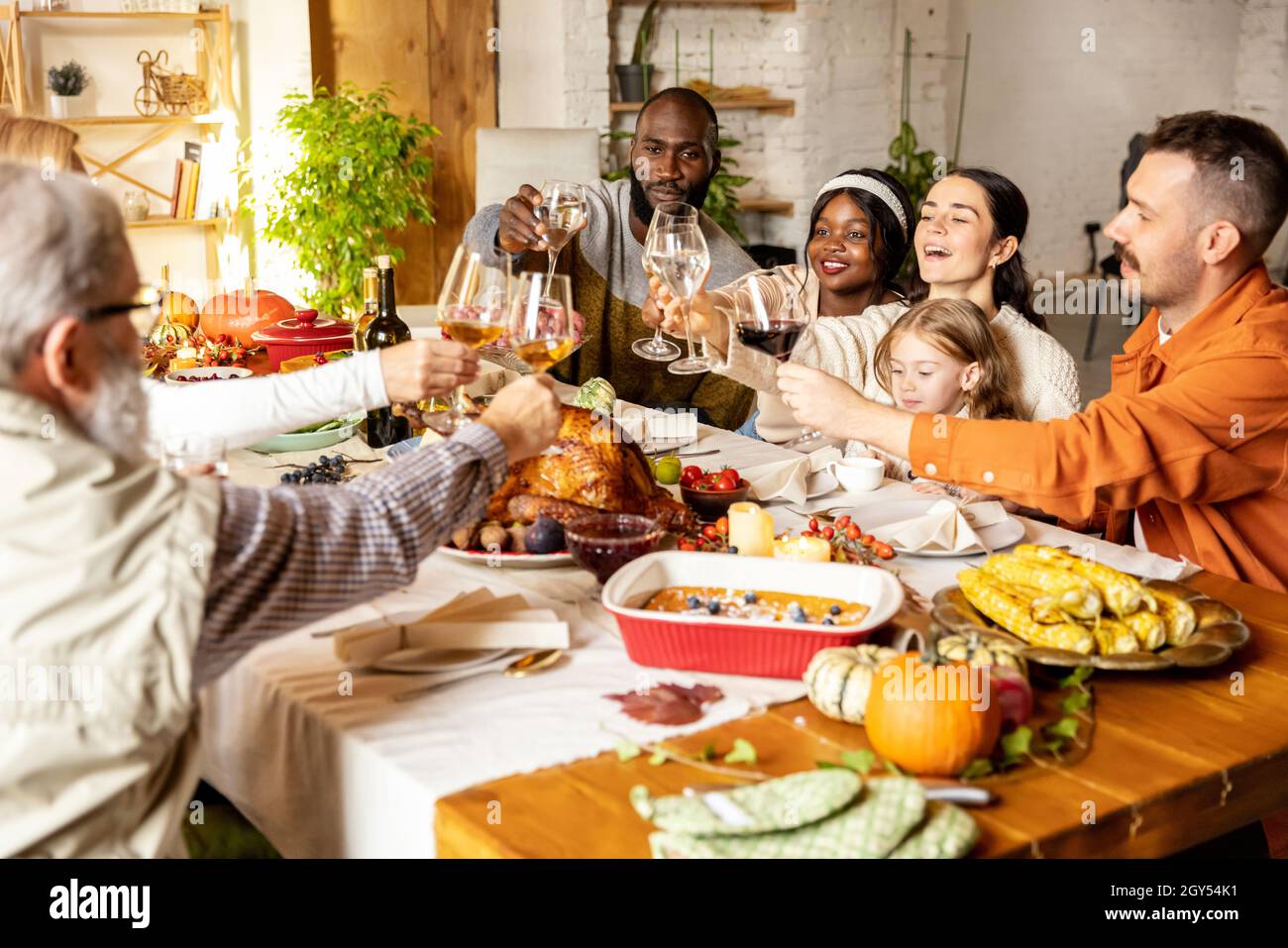 Happy Thanksgiving dinner party with family and friends with turkey and holiday traditional food, dishes on table. Stock Photo