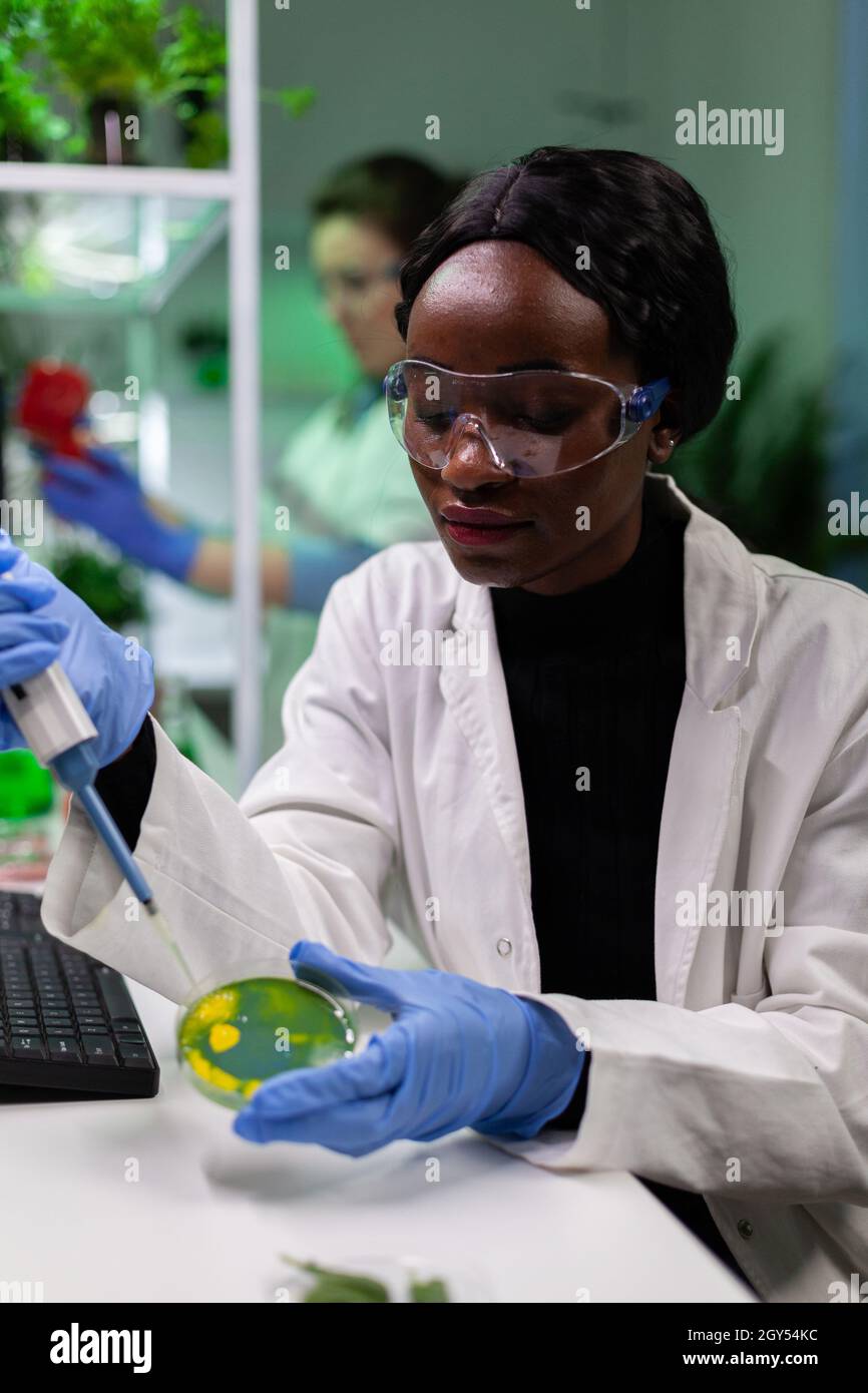 African american biologist scientist dropping liquid using micropipette
