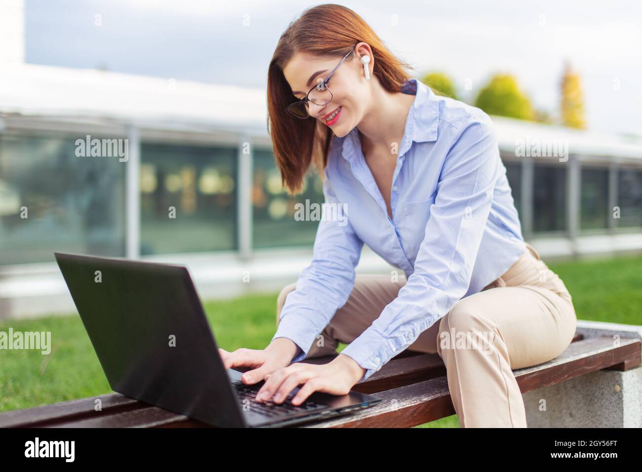 Young white collar Caucasian woman using laptop in park, wireless communication Stock Photo