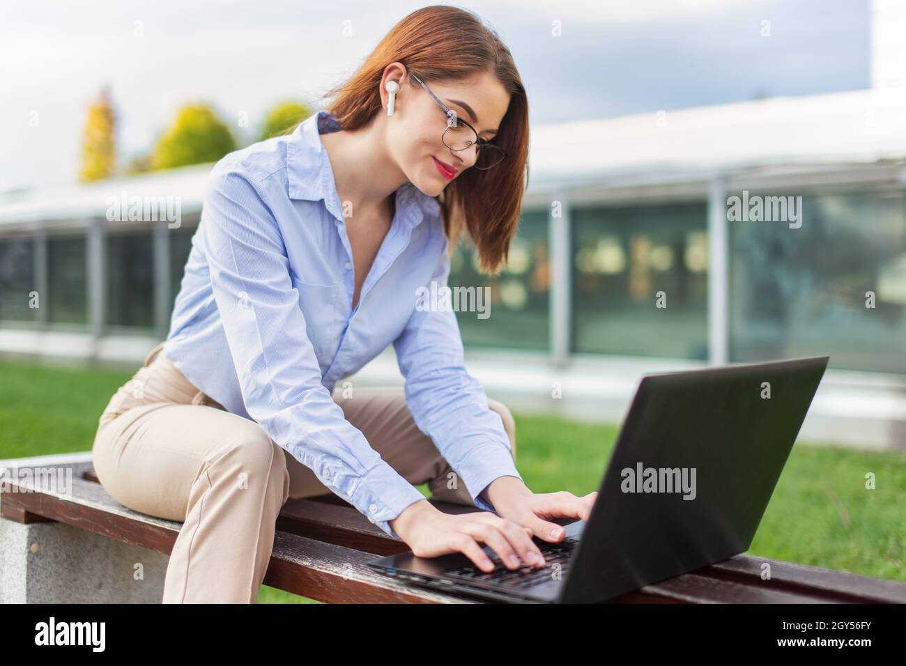 Young university student entrepreneur Caucasian woman using laptop in park, wireless communication Stock Photo