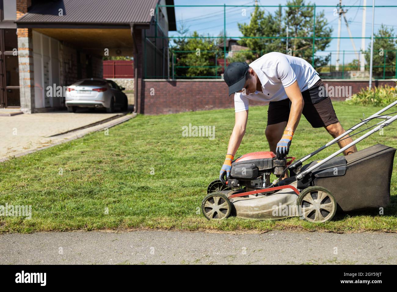 Man closes the fuel tank cap of a lawn mower after refueling Stock