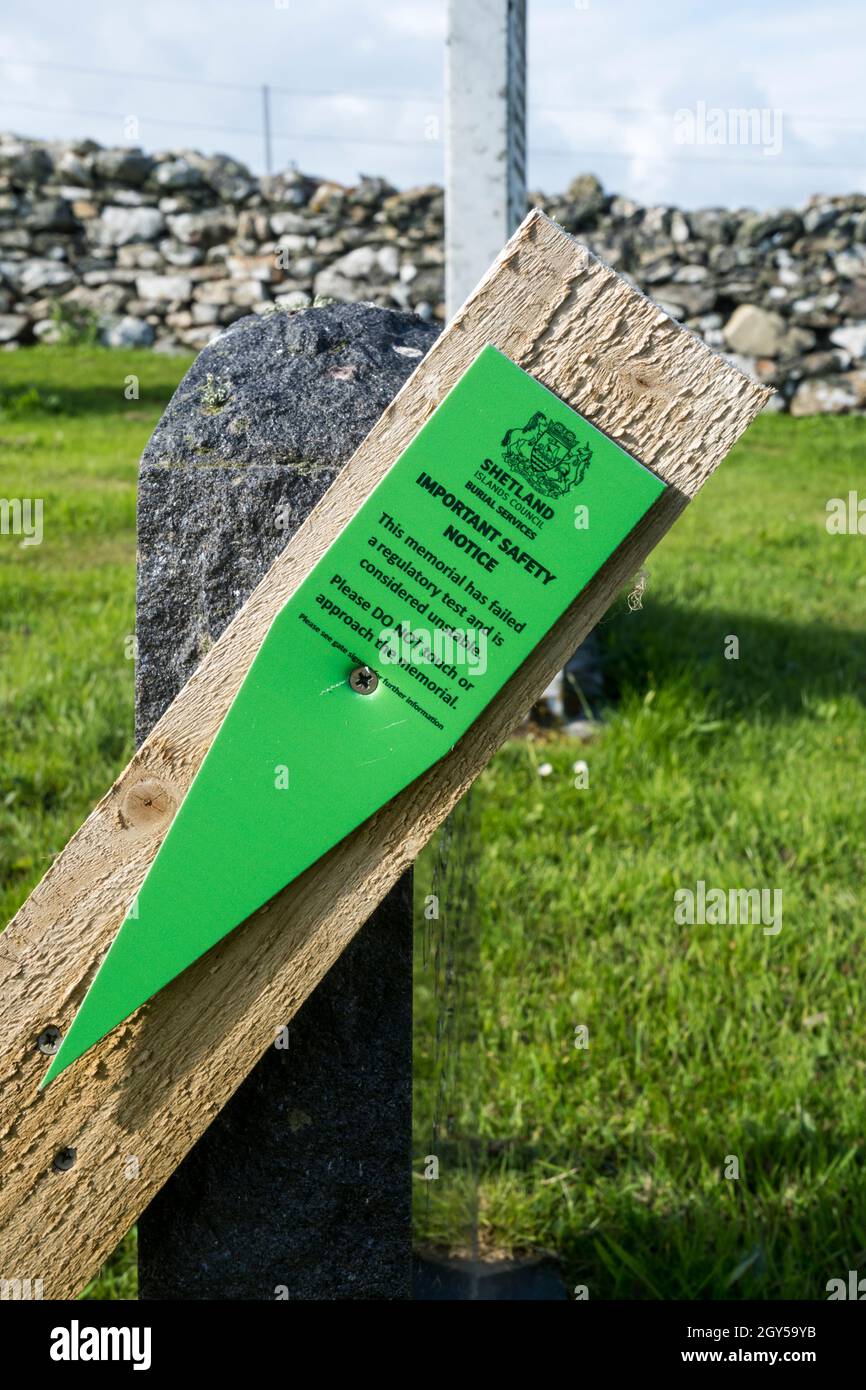 Wooden support & important safety notice sign on an unstable gravestone at Lunda Wick on Unst, Shetland. Stock Photo