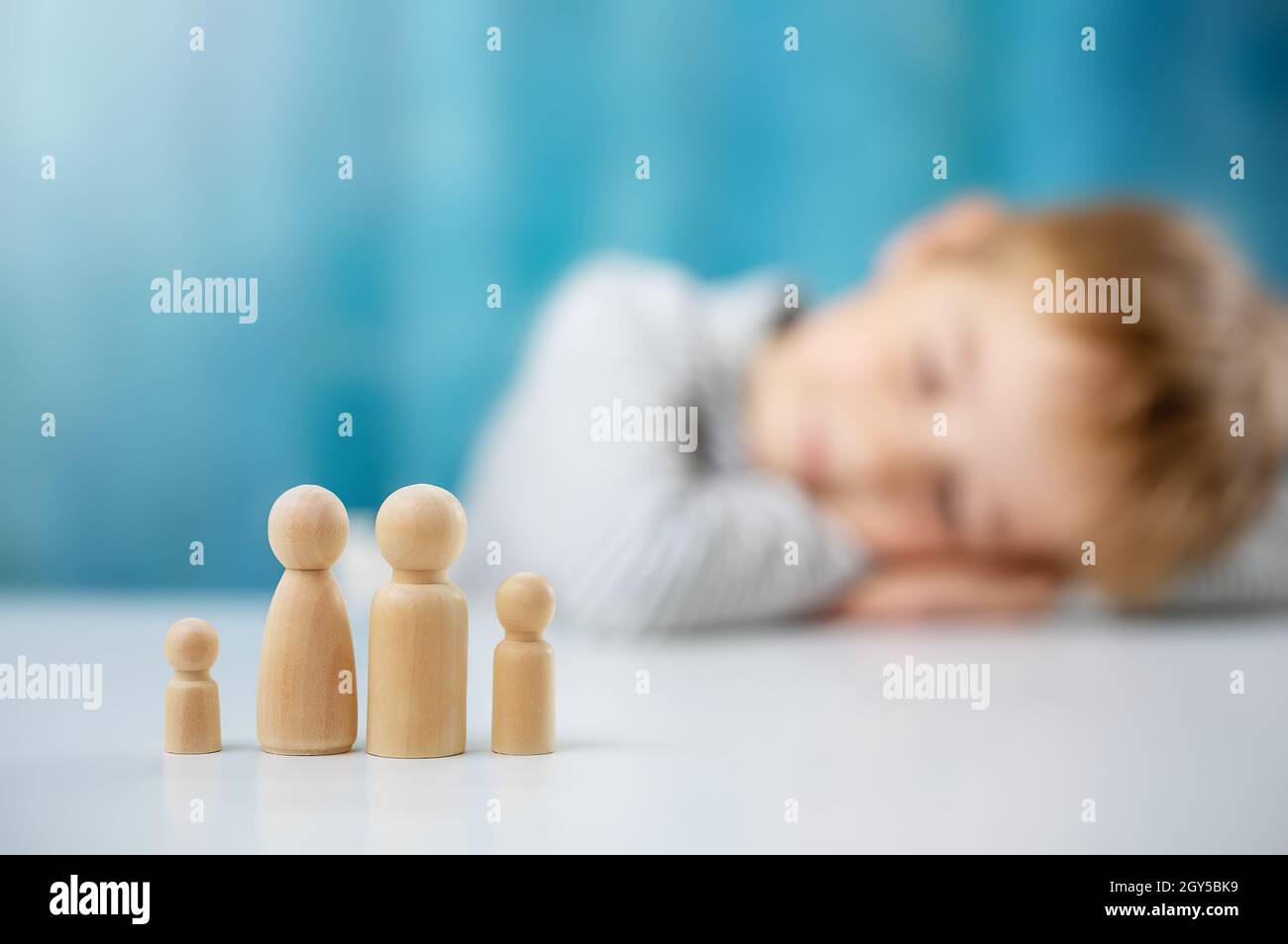 Child with wooden figures of the family on the blue background Stock Photo