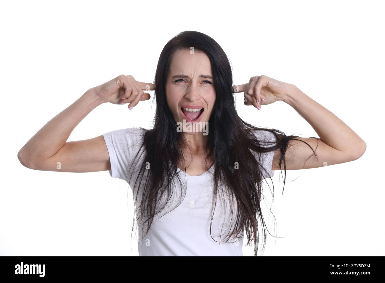 Portrait of young screaming woman covering her ears with fingers. Stock Photo