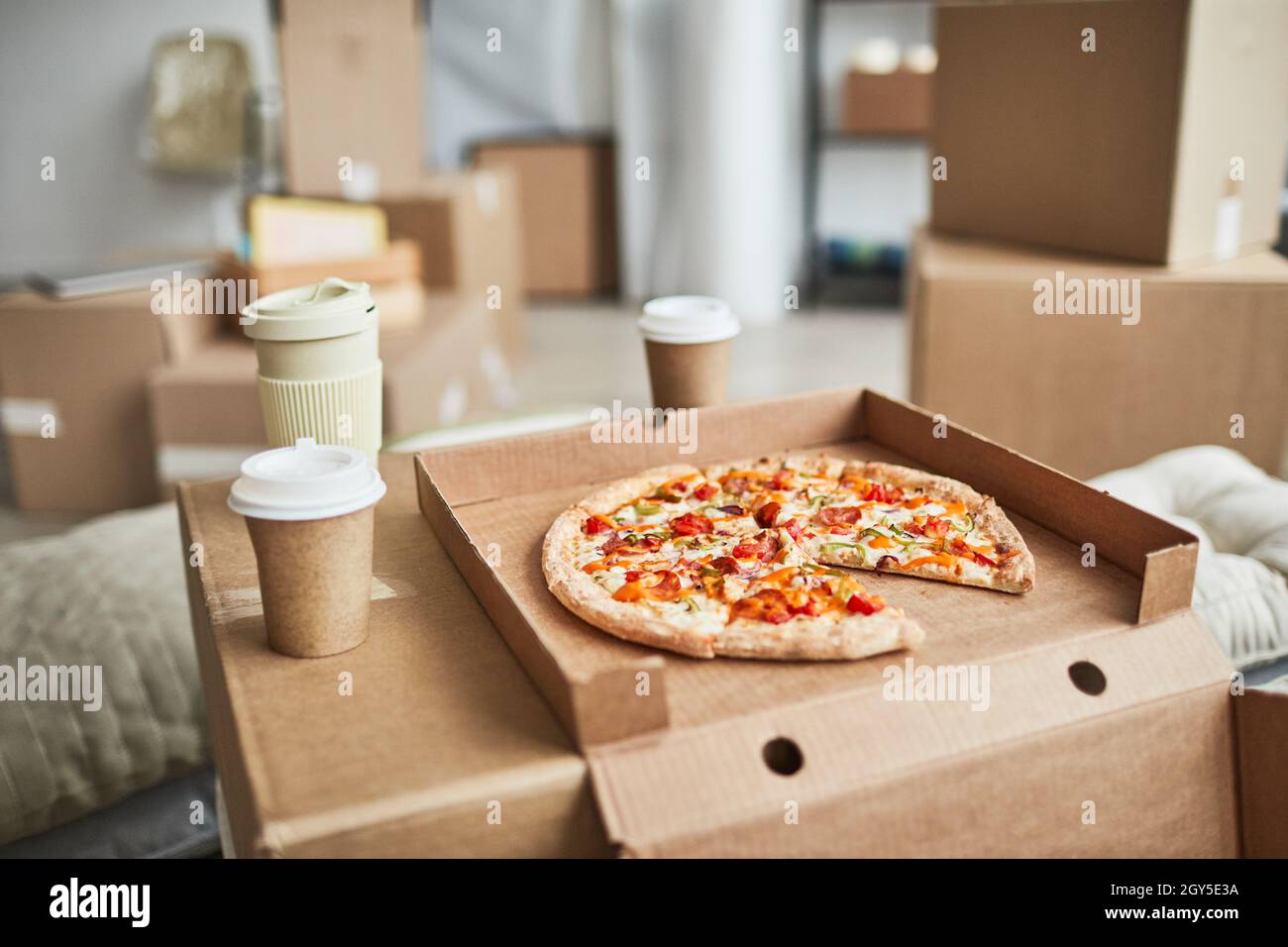 Close up background image of pizza on cardboard box as makeshift table in empty room while family moving in to new house Stock Photo