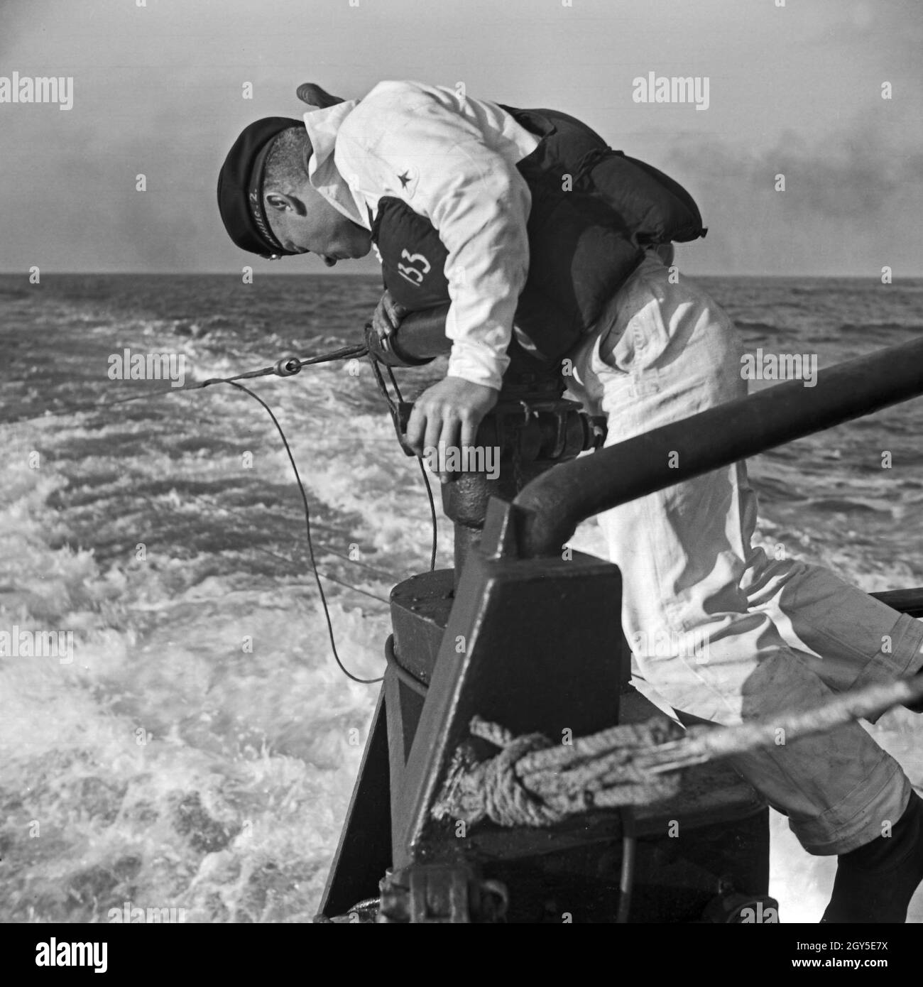 Ein Matrose der 2. Minensuch Flotille bei der Sicherung auf einer Übung auf Ihren Minensuchbooten, Deutschland 1930er Jahre. Sailor of a minesweeper at an exercise on his mindsweeper, Germany 1930s. Stock Photo