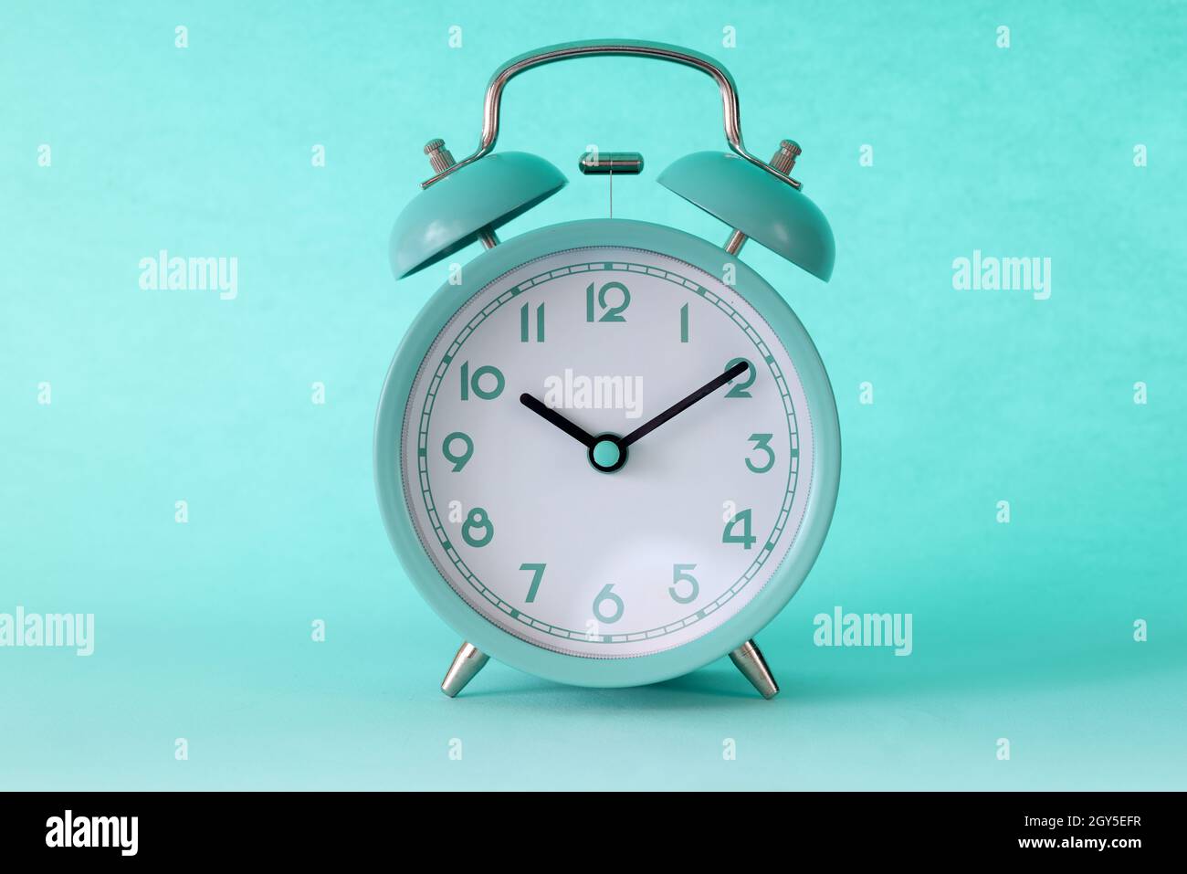 Turquoise classic alarm clock at ten in morning on mint background Stock Photo