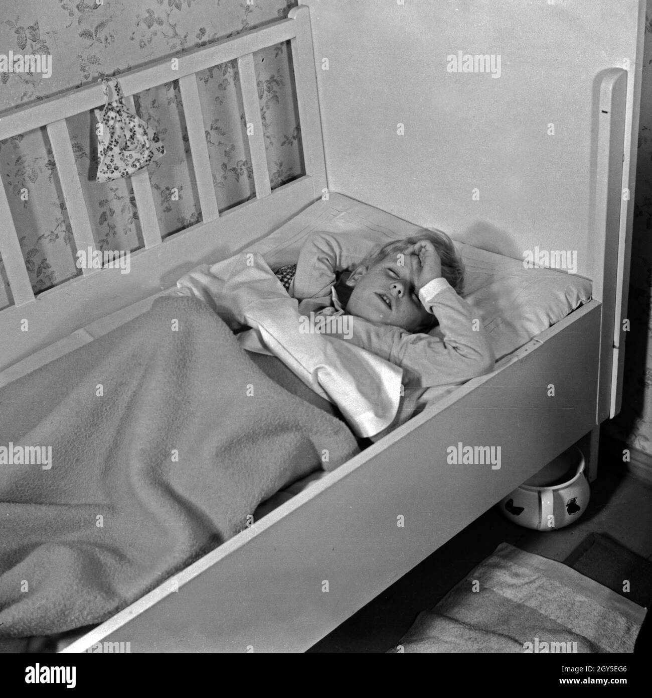 Ein kleiner Junge stellt sich schlafend in seinem Kinderbett, Deutschland 1930er Jahre. A little boy pretending to sleep, Germany 1930s. Stock Photo
