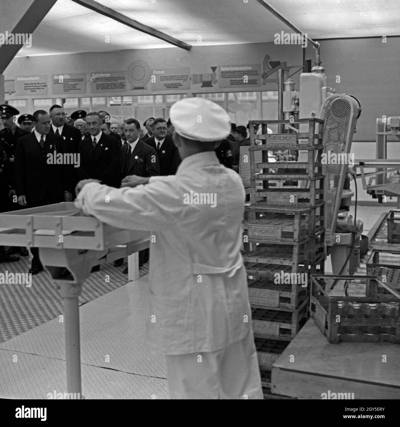 Auf der Internationalen Milchwirtschaftlichen Ausstellung in Berlin 1937 wird eine Maschine zur Frischkäseherstellung vorgestellt, die von einer Gruppe Offizieller besichtigt wird, Deutschland 1930er Jahre. At the international dairying exhibition in Berlin 1937 a machine to process cream cheese is presented to a group of Nazi officials, Germany 1930s. Stock Photo