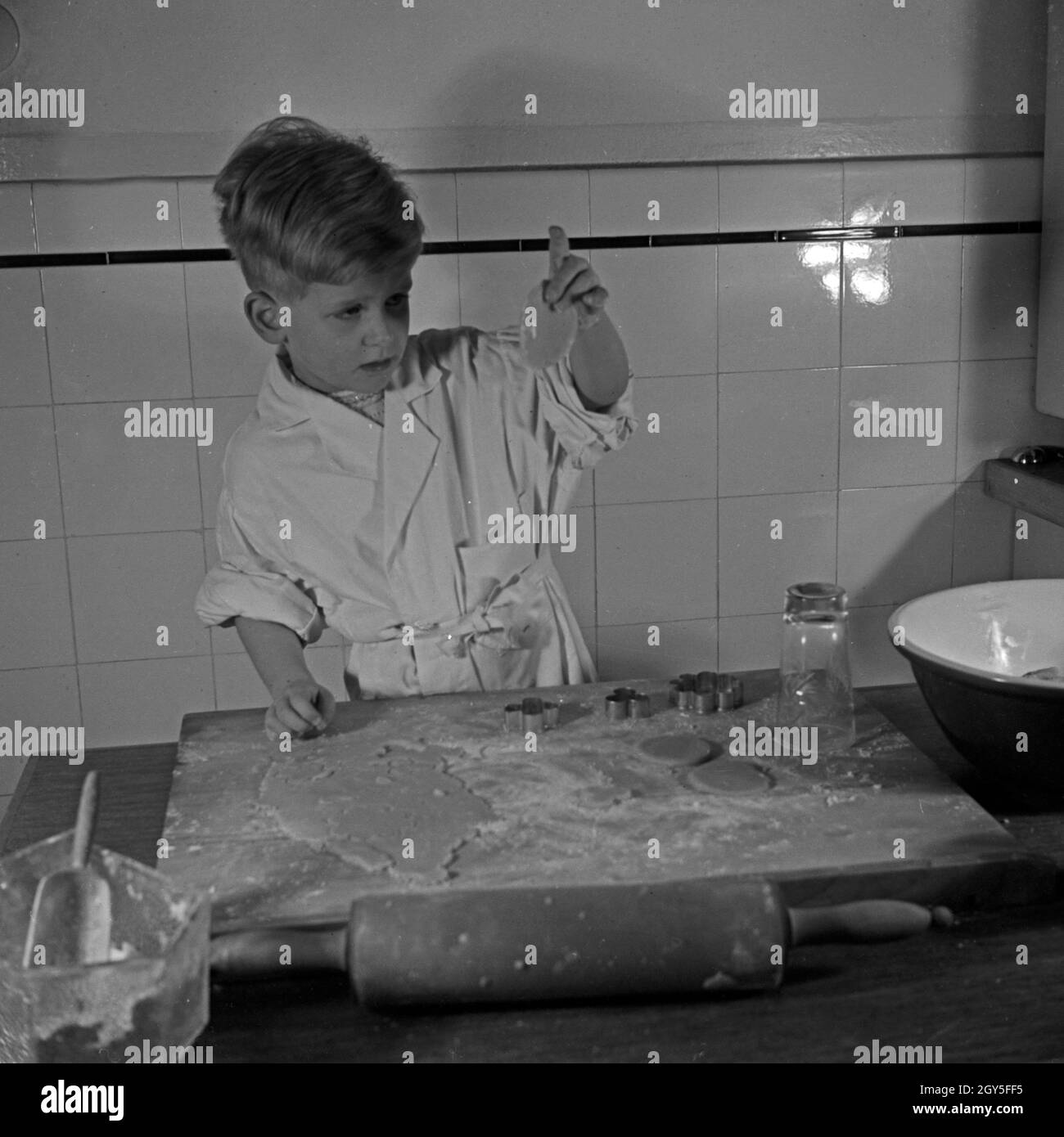 Ein kleiner Junge formt in der Küche aus Teig die Weihnachtsplätzchen, Deutschland 1930er Jahre. A little boy shaping dough for christmas cookies, Germany 1930s. Stock Photo