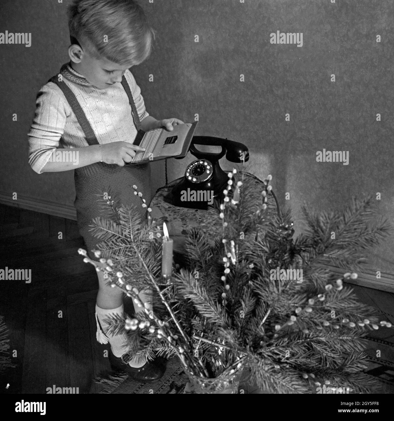 Ein kleiner Junge hat das Telefonregister und das Telefon geholt, um den Weihnachtsmann anzurufen, Deutschland 1930er jahre. A little took the address book and the telephone to give Santa a call, Germany 1930s. Stock Photo