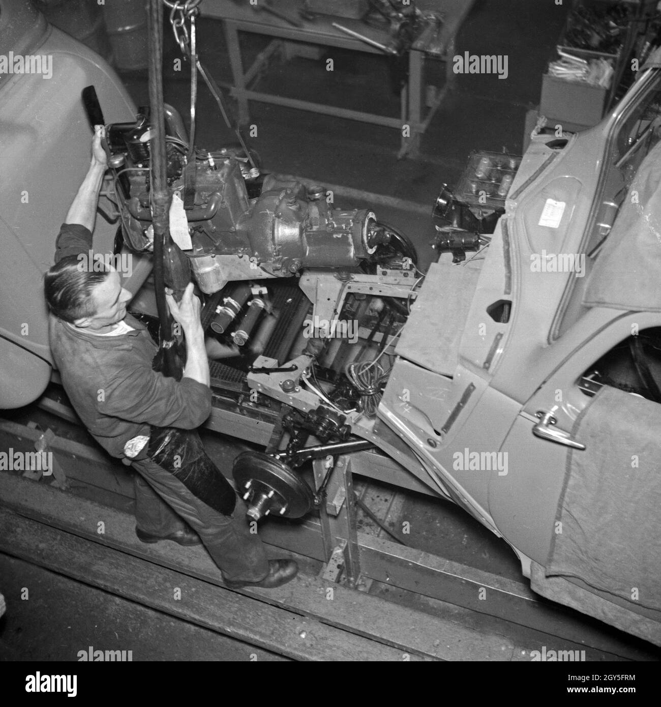 Ein Arbeiter der Ford Werke in Köln Niehl am Fließband mit Karosserien, Deutschland 1930er Jahre. A worker at the conveyor belt of the Ford factory at Cologne, Germany 1930s. Stock Photo