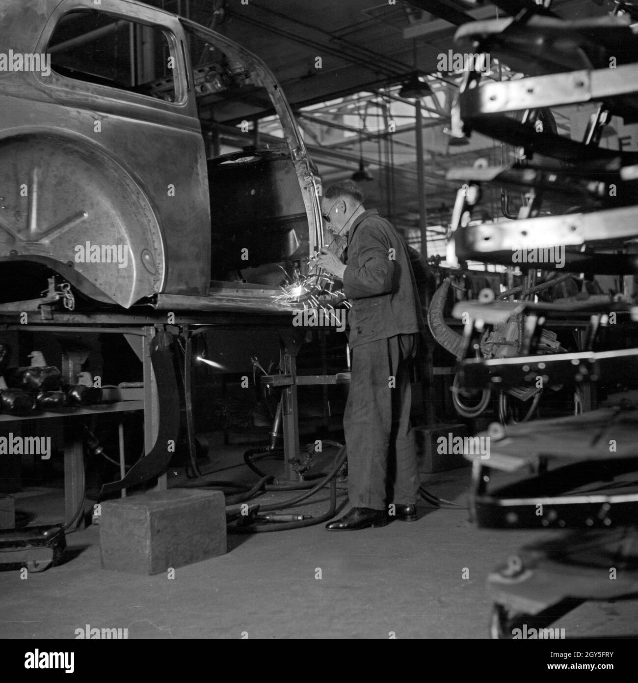 Ein Arbeiter der Ford Werke in Köln Niehl am Fließband mit Karosserien, Deutschland 1930er Jahre. A worker at the conveyor belt of the Ford factory at Cologne, Germany 1930s. Stock Photo