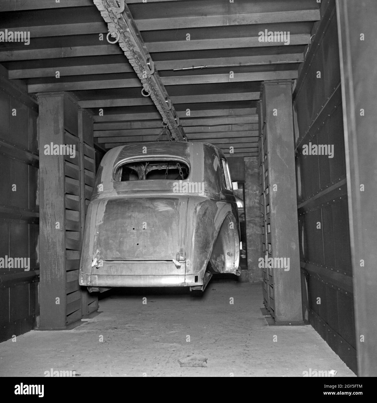 Eine Karosserie wird durch verschiedene Arbeitsgänge geschoben in den Ford Werken in Köln Niehl, Deutschland 1930er Jahre. A chassis is driven through various work stations at the Ford factory at Cologne, Germany 1930s. Stock Photo