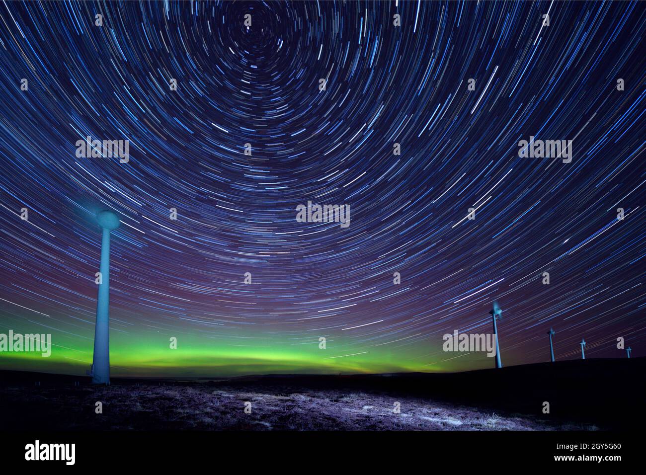 Star trails and Aurora Glow above Hammars Hill wind turbines, Orkney Isles Stock Photo