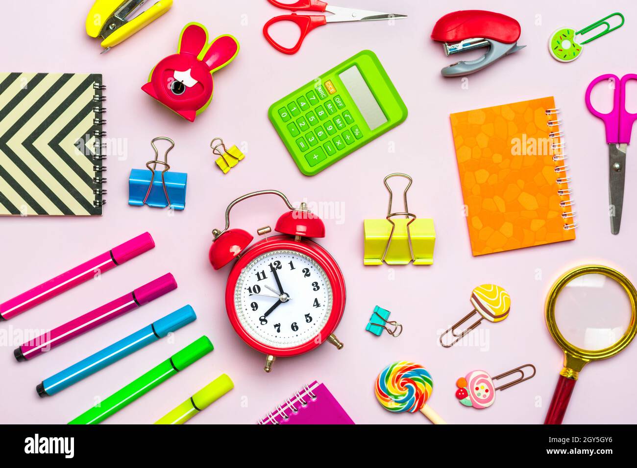 Frame from school and office supplies Paper clips, scissors, pens, felt-tip pens, sharpener, calculator, stapler isolated on pink background Flat lay Stock Photo