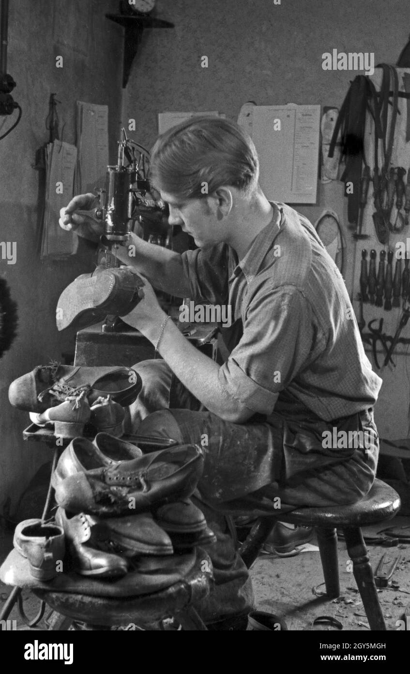 Schuhmacher bei der Arbeit, Deutschland 1940er Jahre. Shoemaker at work ...