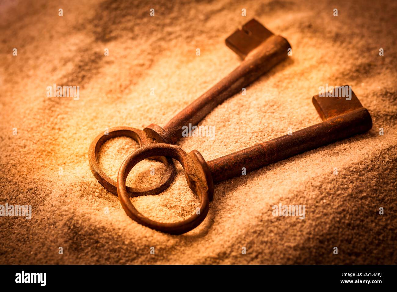 Two old rusty keys in sand in warm tones Stock Photo