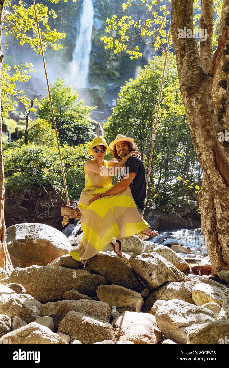 Young loving couple swing on a swing in the woods. Very romantic situation. It's summer Stock Photo