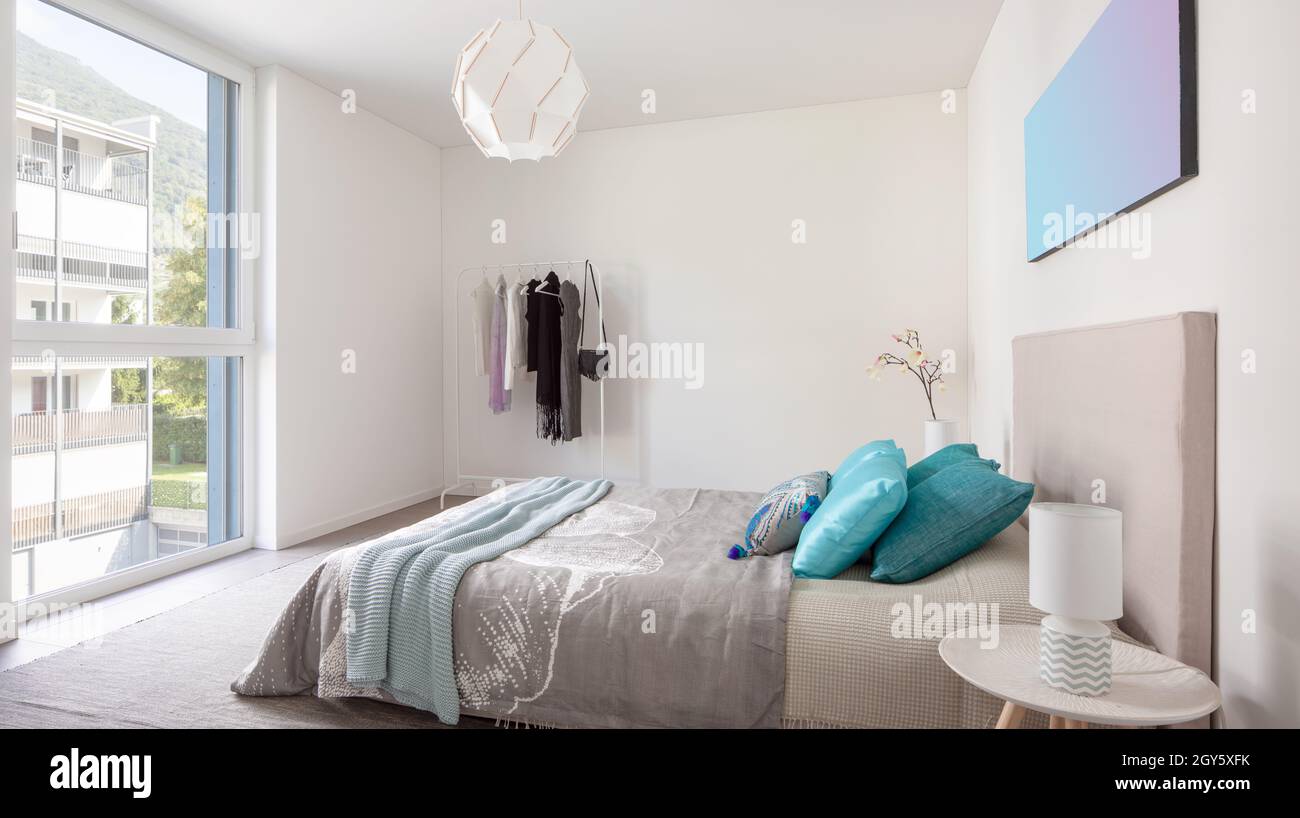 Elegant bedroom with white walls, double bed and lots of pillows. Nobody inside Stock Photo