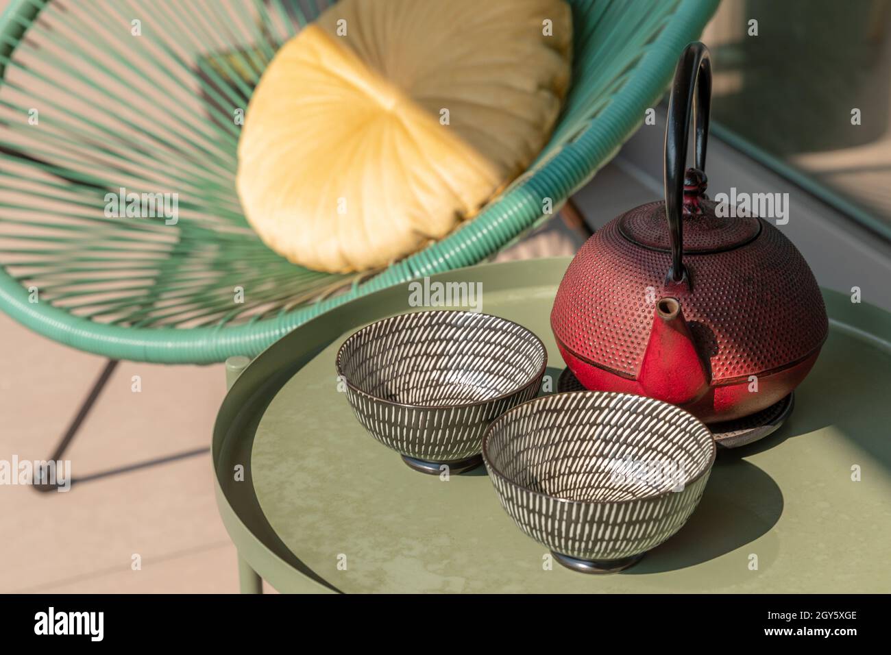 Elegant corner of a terrace of a modern house with two armchairs and a Chinese tea with two cups. Sunny summer day Stock Photo