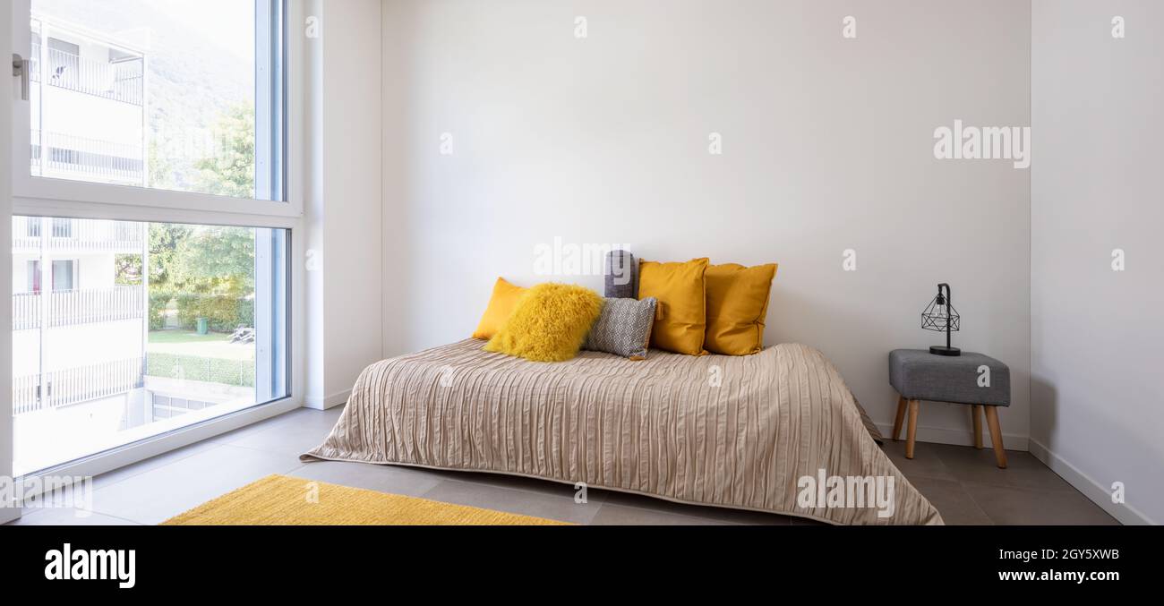 Nice bedroom with a bed, sidetable and lots of pillows. Detail of the bed with a large white wall, perfect for copy space. Very romantic room. Concept Stock Photo